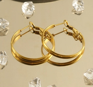 Detailed close-up of polished 18k gold-plated stainless steel hoop earrings on mirror base