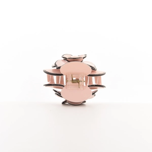 Detail view of a pink camellia hair claw with black edges and metal spring mechanism