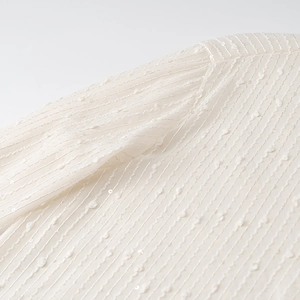 Detail view of cream white chiffon fabric with sequin and 3D jacquard striped texture