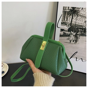 Close-up of green lychee textured leather handbag with gold buckle and detachable strap