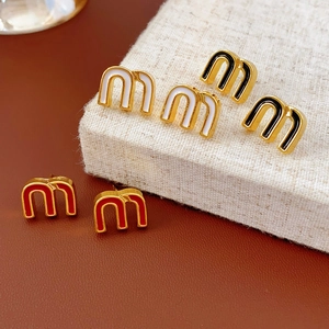 Detail of m-shaped gold earrings with white, black, and red enamel finish details