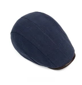Top view of blue newsboy cap with brown leather brim and fine woven texture details