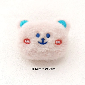 Close-up of a pink plush bear pin with blue ears and red blush, size 6cm by 7cm