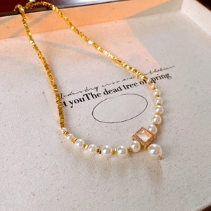 Gros plan d'un collier de perles plaqué or 18 carats avec pendentif carré serti