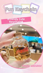 Macro shot of liquid-filled soda bottle keychain with gold lobster clasp and red logo