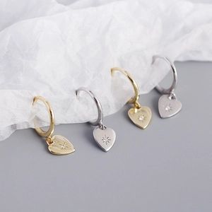 Close-up of heart-shaped drop earrings with starburst setting and sparkling gems