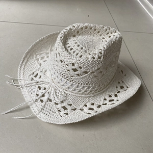 Detail of white hollow woven straw cowboy hat featuring side decorative string bow
