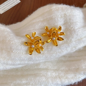 Detailed macro shot of vintage floral stud earrings with pearls on a knit texture