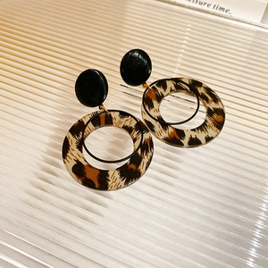 Macro detail of gold plated leopard print hoop earrings with acrylic texture and round studs