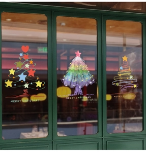 Close-up of hand-drawn Christmas tree window stickers with stars and hearts on glass