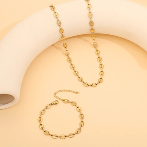 Close-up of golden coffee bean link necklace and bracelet set on a white stand