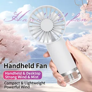 White portable handheld misting fan with water tank held against an outdoor scenic background