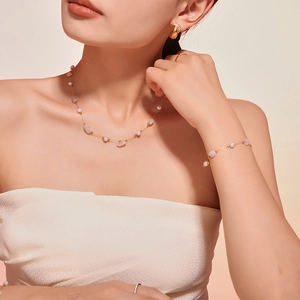 Set collana in oro con pietre naturali rosa e perle bianche su una modella elegante