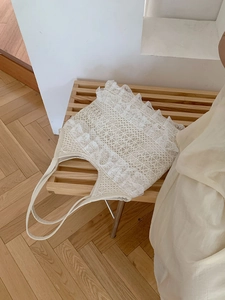 Detail shot of white lace tote bag with delicate crochet floral pattern and wavy edges
