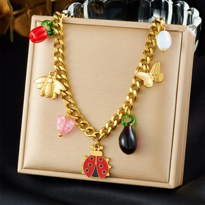 Detail of gold chain bracelet with ladybug bee butterfly and pepper charms on jewelry box