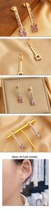 Detail of key-shaped gold drop earrings with purple zircon stones on luxury satin background