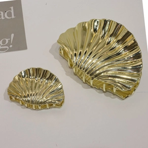 Set of two golden shell-shaped alloy hair claws in different sizes on white surface