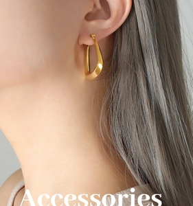 Macro detail of U-shaped gold plated earrings showing high-gloss finish and modern design