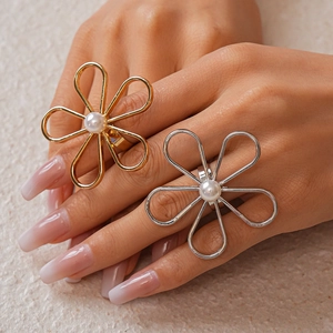 Detail of a large hollow flower ring in gold and silver finish with a center pearl