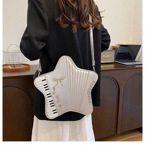 Star-shaped silver crossbody bag with piano key pattern and metallic charms detail