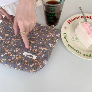 Détail d'une trousse de maquillage en velours côtelé fleuri sur une table de thé l'après-midi