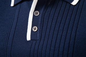 Macro shot of navy blue knit polo shirt collar with white trim and button details