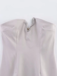 Close-up of rhinestone V-neck detail on a beige strapless bodycon mini dress