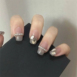 Close-up of nude and grey press-on nails with glitter, rhinestones, and ice shards