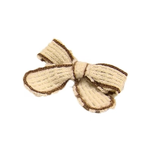 Detailed close-up of a handmade knitted beige bow with dark brown trim for DIY crafts