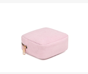 Detailed view of pink textured cosmetic bag with gold zipper and square minimalist design