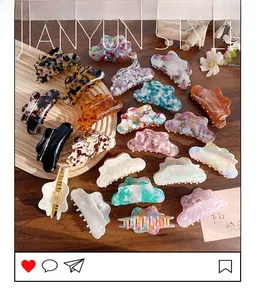 Flat lay of diverse cloud-shaped acetate hair claws on a wooden tray and table