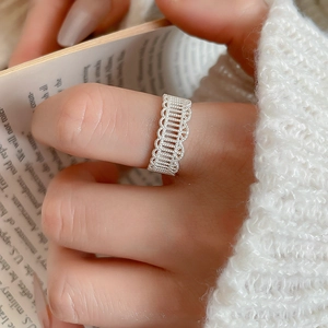 Detailed view of silver lace hollow flower ring on hand with elegant book background