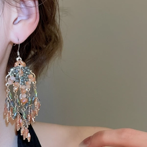 Close-up of bohemian gold tassel earrings featuring colorful translucent beads