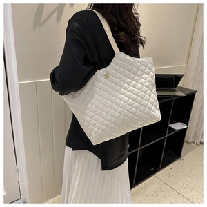 Détail du sac cabas matelassé blanc avec logo fleur dorée et bandoulière beige clair