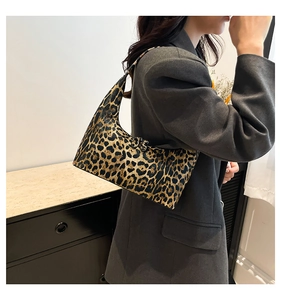 Close-up of stylish leopard print bucket bag worn by model in a minimalist room