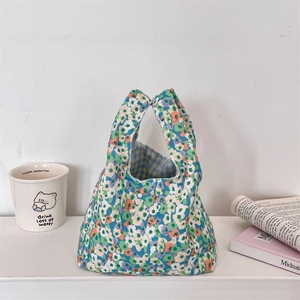 Detail view of floral corduroy wrist bag with blue gingham lining and canvas handles