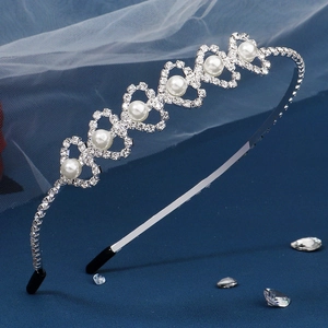 Detail of silver heart headband with white pearls and sparkling rhinestones on blue fabric