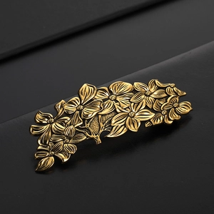 Vintage golden floral metal hair clip with intricate embossed flower and leaf designs