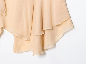 Detail of layered ruffle hem on apricot chiffon blouse with a flowy irregular drape