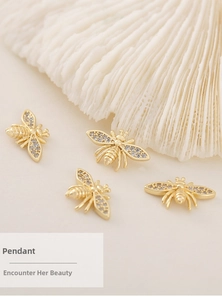Detail shot of four golden bee pendants with cubic zirconia wings on a white shell