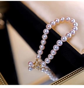 Detailed close-up of pink pearls on black velvet with a golden lobster clasp and chain