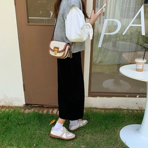Borsa a sella in tela crema con finiture in pelle marrone indossata da una modella
