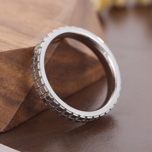 Detailed close-up of a silver grid patterned stainless steel ring on a wooden stand
