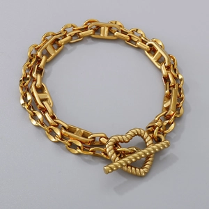 Macro detail of gold titanium double-layer bracelet with heart toggle and H-link chain