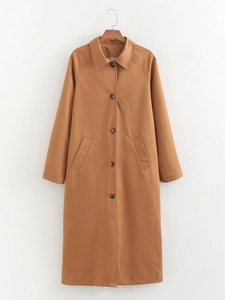 Close-up of khaki long trench coat featuring brown buttons and side pockets on a hanger
