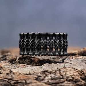 Vintage oxidized stainless steel bone-shaped ring on a rugged textured surface