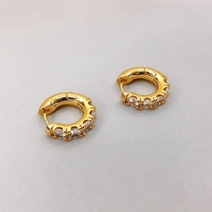 Close-up of gold round earrings with pavé-set white cubic zirconia stones