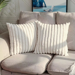 Detail of white faux rabbit fur pillow with striped texture on a beige sofa