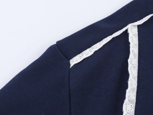 Gros plan sur tissu tricoté bleu marine avec dentelle blanche sur la couture d'épaule