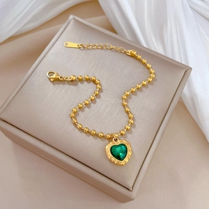 Detail of gold beaded bracelet with green heart pendant on a premium display box